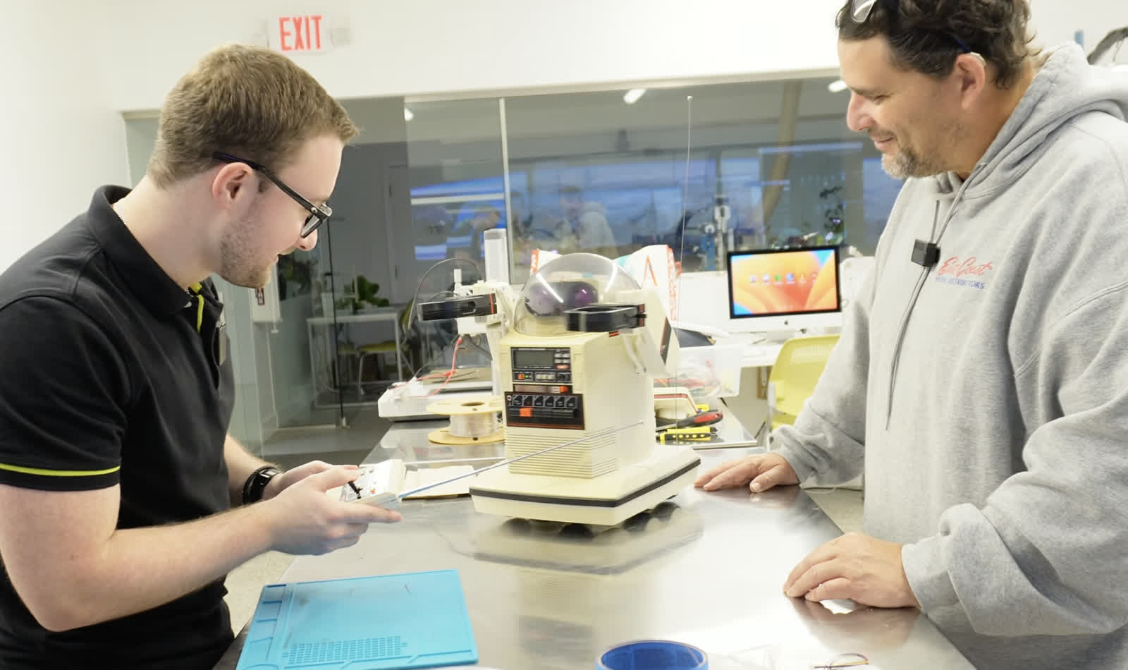 Omnibot on a workbench at Moonlighter FabLab with two makers working on it